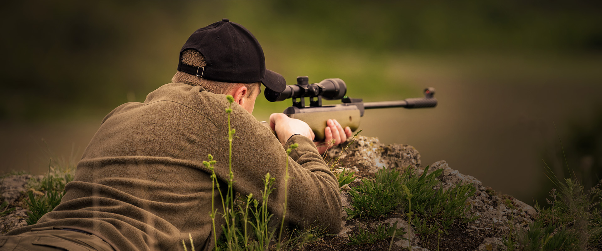 Ein Jäger liegt in Anschlagsposition mit einem Zielfernrohr-Gewehr, trainiert präzises Schießen im Rahmen des realitätsnahen Jagd- und Schießtrainings von Schiess-Kino Cramberg.